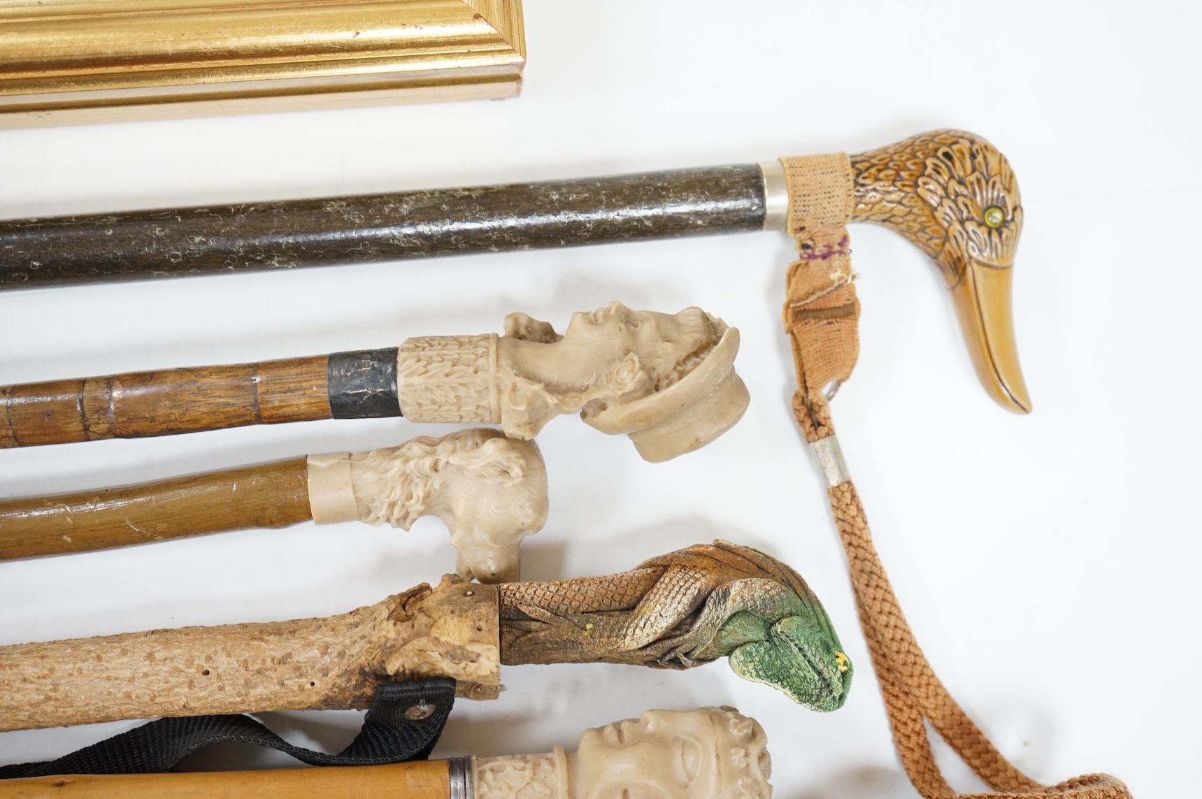 A collection of eight mostly moulded resin mounted walking canes to include one in the form of a lizard, largest 93cm in length